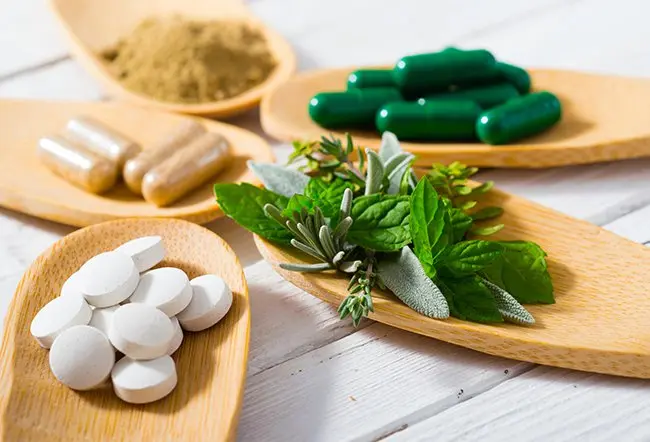 Medication pills, supplements, and fresh herbs (mint and rosemary)